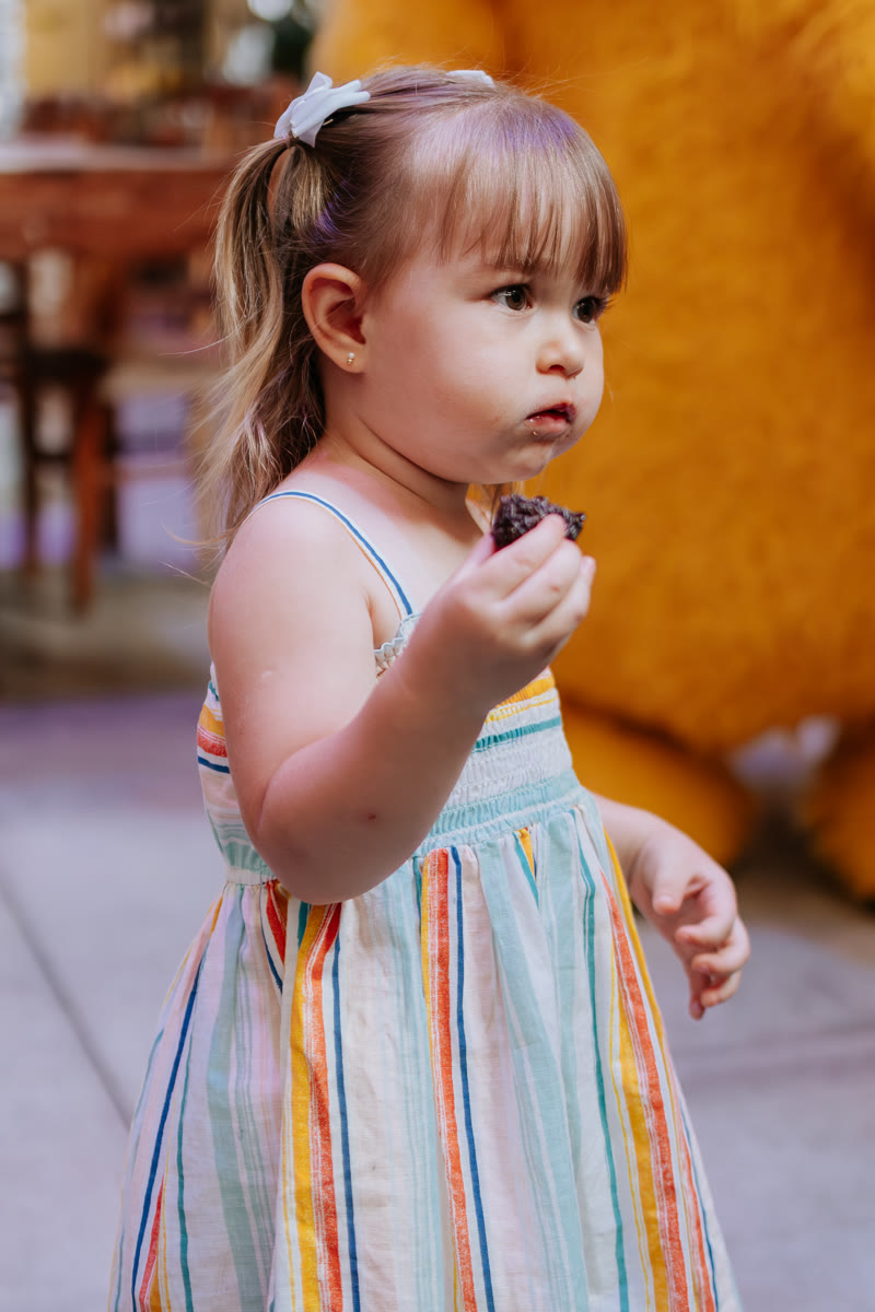 Menina de vestido listrado comendo docinho