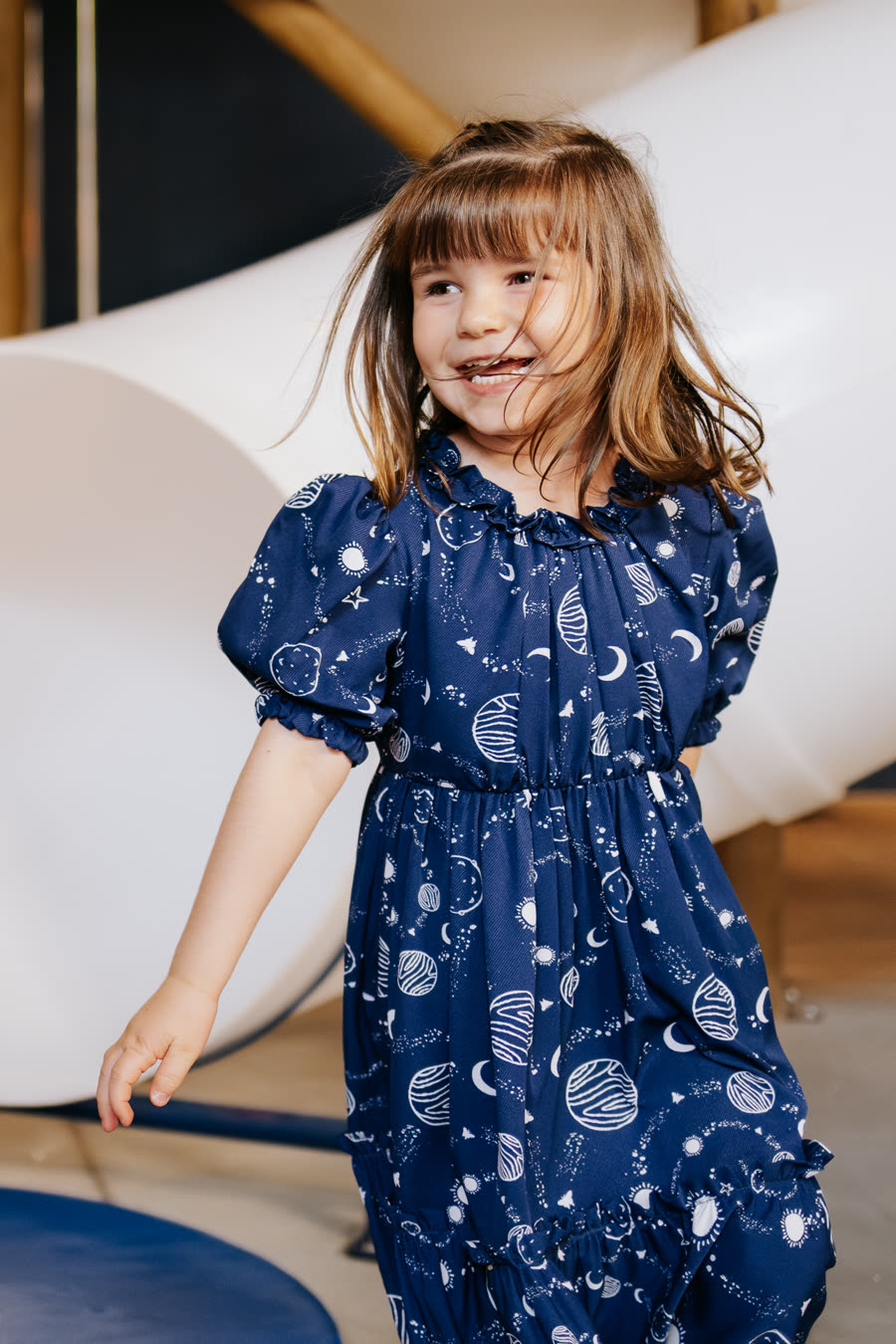 Menina de vestido azul de planetas sorrindo