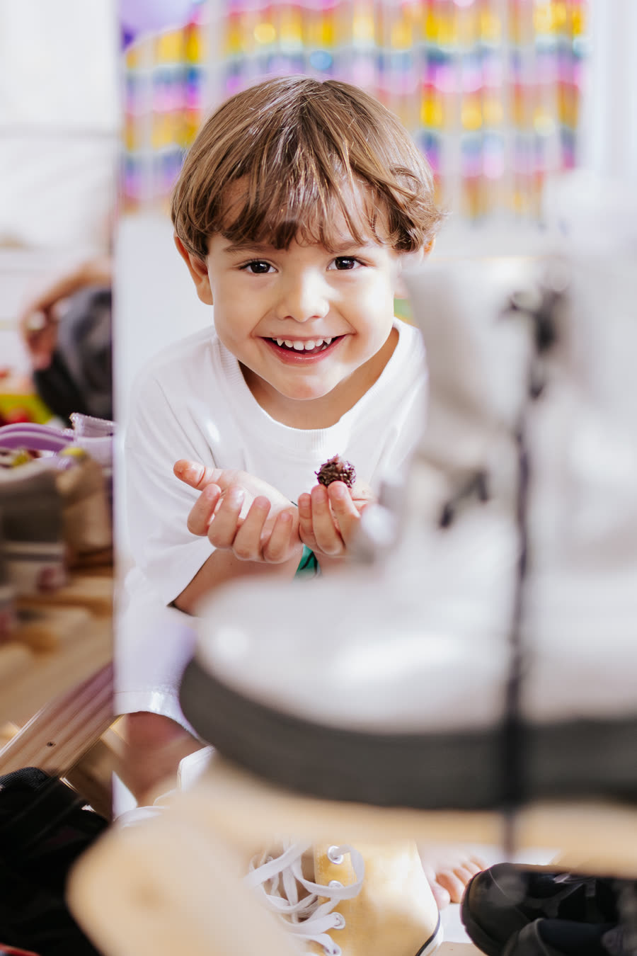 Menino sorrindo com um brigadeiro na mão